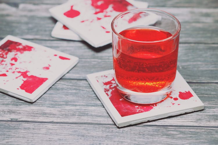 Serve your delicious drinks on these bloody coasters this Halloween! This blood-splattered coaster DIY with ceramic tiles is super easy and inexpensive!