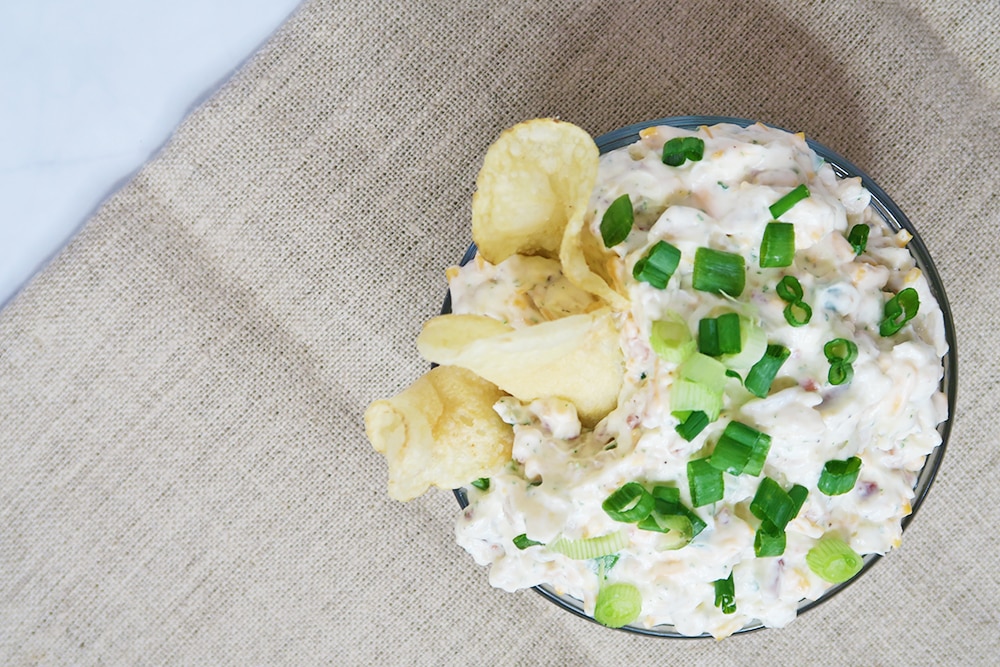 This simple Cheddar Bacon Ranch Dip is the solution you've been waiting for when it comes to what to bring to your next holiday or tailgating party. #chipdip #bacondip #veggiedip #easyappetizer #crackerspread #tailgatingappetizer