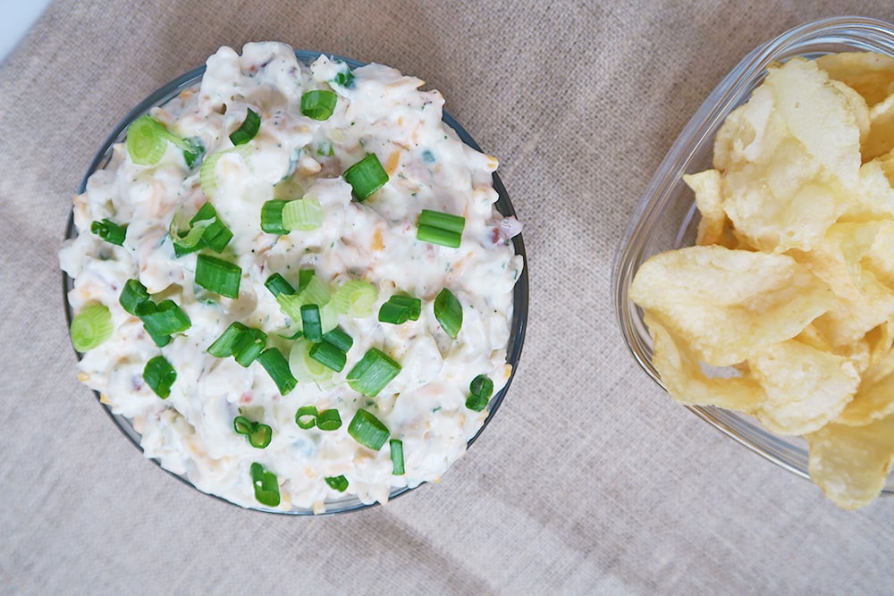 This simple Cheddar Bacon Ranch Dip is the solution you've been waiting for when it comes to what to bring to your next holiday or tailgating party. #chipdip #bacondip #veggiedip #easyappetizer #crackerspread #tailgatingappetizer