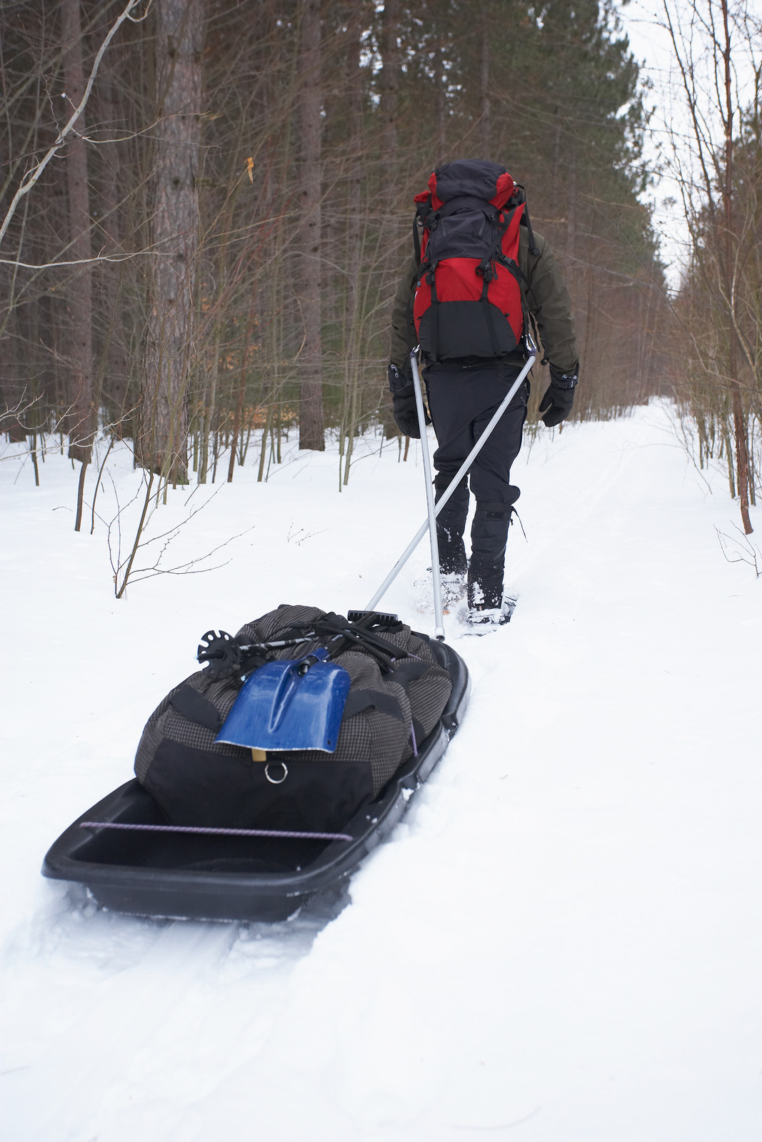 Man pulling sled while snowshoeing